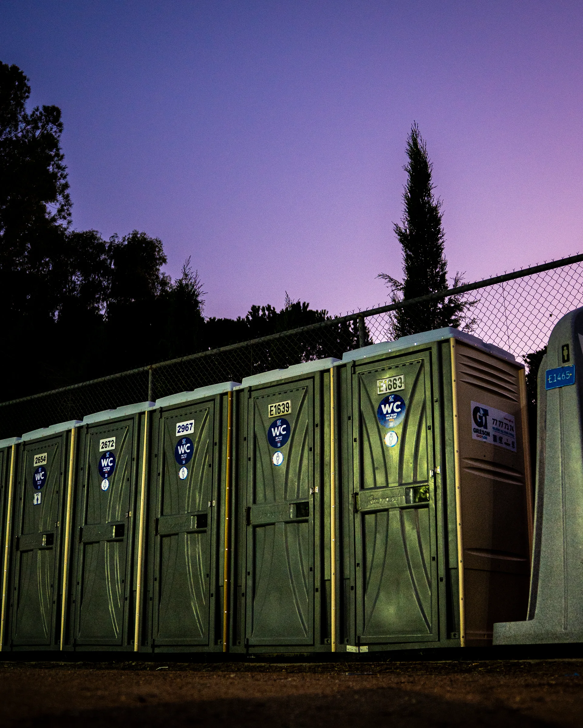 Row of Greson Easy Loo portable toilets lined up at dusk
